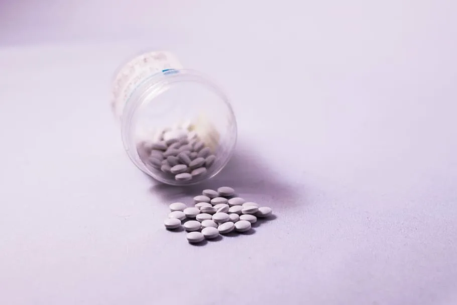 Human medication tablets spilling from a bottle, a common household poison for pets